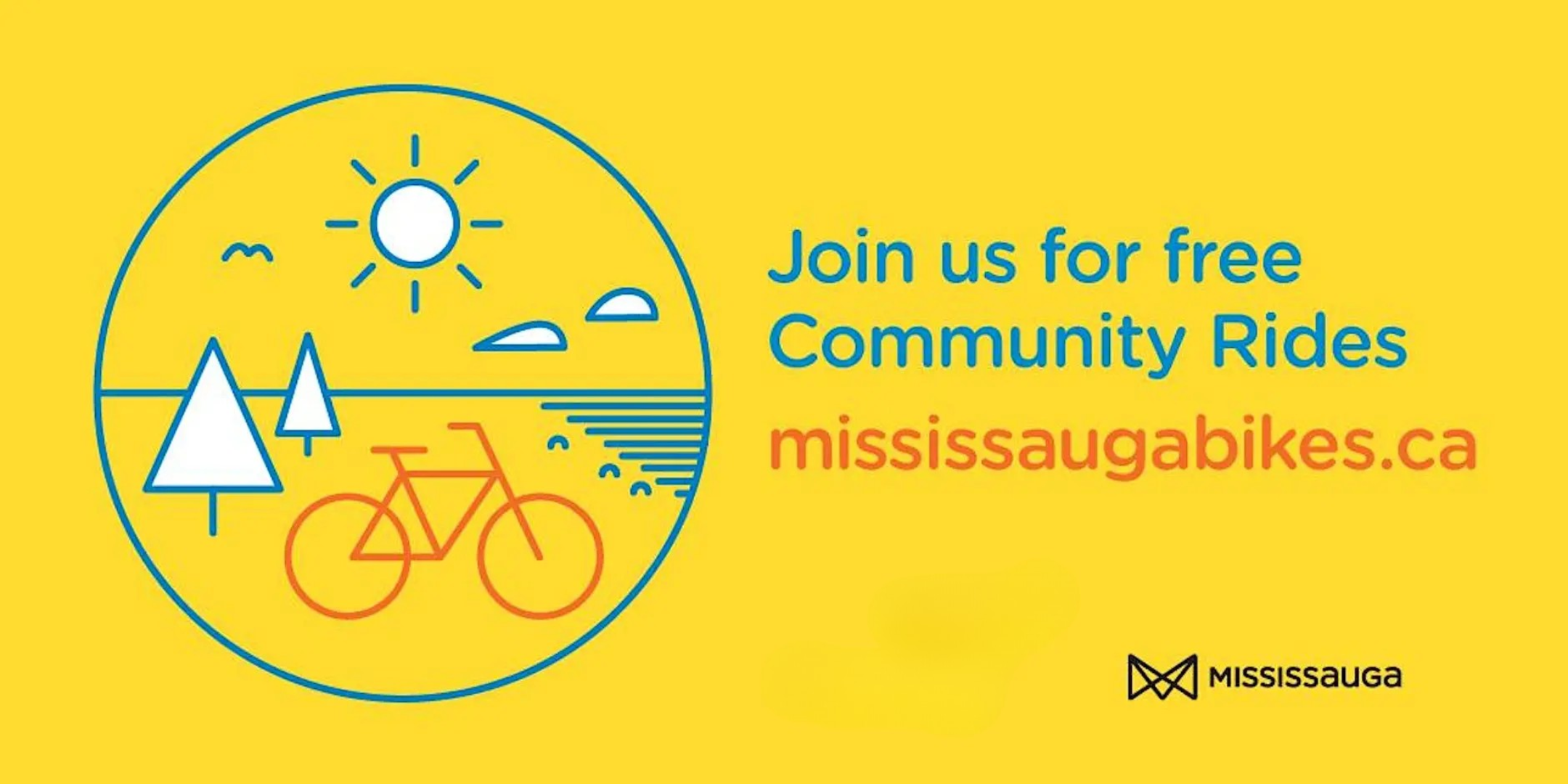 A group of smiling cyclists ride through a park.